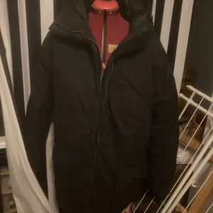 Svart vinterjacka med huva - Snygg svart vinterjacka med dragkedja och huva. Perfekt för kalla dagar. Jackan har en klassisk design och är både stilren och funktionell.
