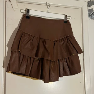 Brun volangkjol - Säljer denna kjolen från Design By Si då den är lite för liten, aldrig använd!! Hittar ingen lapp med storlek men passar xs/s💗