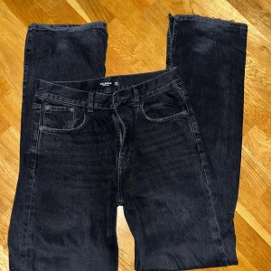 Svarta jeans från Pull&Bear - Säljer ett par svarta jeans från Pull&Bear i herrstorlek M. Jeansen har en klassisk femficksdesign och är tillverkade i ett slitstarkt material. Perfekta för en avslappnad stil. Hög midja, tajtare passform runt midjan och en rak/lösare passform på benen. Supersmickrande passform!
