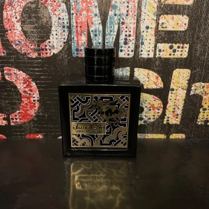 Qaed Al Fursan Eau de Parfum från Lattafa - Säljer en elegant och mystisk parfym, Qaed Al Fursan från Lattafa. Flaskan är svart med ett gyllene hästmotiv och geometriskt mönster. Den kommer i en matchande svart kartong med samma design. Perfekt för den som söker en unik doftupplevelse. Byten är också intressant 