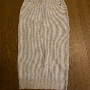 Beige ribbad kjol - Snygg beige ribbad kjol i stickat material. Kjolen har en klassisk design med en bekväm passform och är perfekt för både vardag och speciella tillfällen.