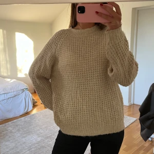 Beige stickad tröja - Mysig beige stickad tröja med långärmad design. Perfekt för kyligare dagar med sin varma och bekväma passform. Enkel och stilren, passar till många olika outfits.