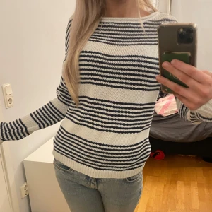 Randig stickad tröja - Säljer en mysig stickad tröja med svarta och vita ränder. Tröjan har långa ärmar och en bekväm passform, perfekt för kyligare dagar. Den är stilren och lätt att matcha med olika outfits.