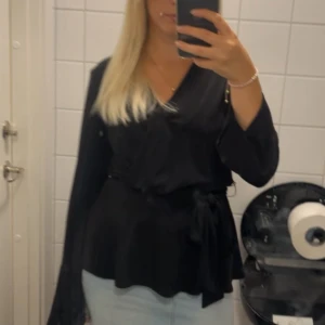 Svart omlottopp från H&M - Snygg svart omlottopp från H&M med knytband i midjan. Passar S och M 