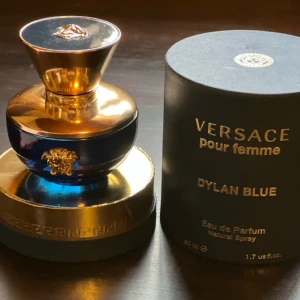 Versace parfym 50ml  - Elegant parfymflaska i blått och guld från Versace. Dylan Blue Pour Femme är en Eau de Parfum med en lyxig och sofistikerad doft. Flaskan har en gyllene kork och det ikoniska Medusa-emblemet. Perfekt för den som vill ha en exklusiv doftupplevelse. 