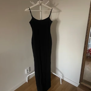 Svart långklänning med tunna axelband - Svart långklänning med tunna axelband. Liten urringning bak i ryggen. Lite glansigare material. Säljer då den är för kort. Aldrig använd