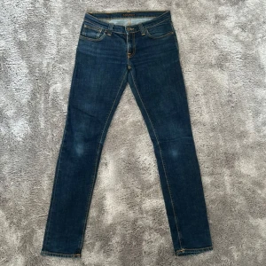 Nudie jeans 29/32 - Säljer ett par snygga mörkblå jeans från Nudie Jeans Co i storlek W29 L32. De har en klassisk femficksdesign och orange sömmar som ger en cool kontrast. Perfekta för både vardag och fest! 🕺