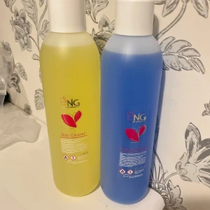 NG Nail Cleaner och clean off solution - Två flaskor från NG, en med gul nagelrengöring och en med blå vätska. Båda flaskorna har en kapacitet på 1000 ml och är försedda med vita skruvlock. Perfekt för nagelvård och rengöring. Säljer tillsammans för 700kr. 500kr/st annars