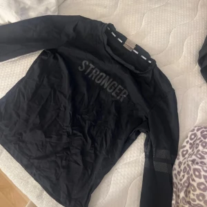 Svart långärmad tröja från Stronger - Säljer en svart långärmad tränings tröja från Stronger med texten 'STRONGER' tryckt på framsidan. Tröjan har används ca 2 gånger och säljer pågrund av att den inte kommer till använding mer. 