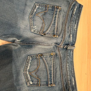 Blå jeans från Diesel - Snygga blå jeans från Diesel med slitna detaljer och en klassisk femficksdesign. De har en straight passform och är perfekta för en avslappnad stil. Jeansens slitningar ger dem en cool och trendig look. Så snygga och get Victoria secret fashion show jeans lågmidjade🩷🩷