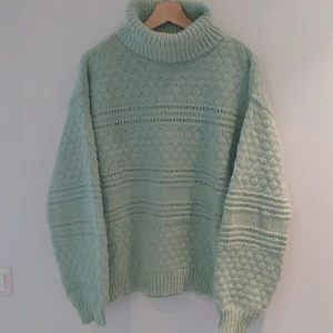 Mintgrön stickad polotröja från Pieces - Säljer en supermysig mintgrön stickad polotröja från Pieces. Den har en härlig ribbad polokrage och ett fint mönster med små hål och ränder. Perfekt för kyliga höst- och vinterdagar. Tröjan är långärmad och har en lös passform som gör den extra bekväm. Ett måste i garderoben för alla som älskar stickade plagg!