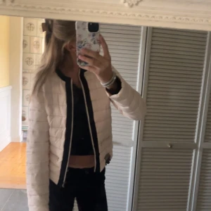 Beige quiltad jacka med svarta detaljer - Säljer en snygg vit rosa Ish jacka med svarta detaljer. Perfekt för höst och vår när du vill hålla dig varm. Väldigt fin använt få gånger kanske har nån liten smutsfläck men det ska gå bort i stvätt💞 (TRYCK INTE PÅ KÖP SKRIV TILL MIG FÖRST!)💞