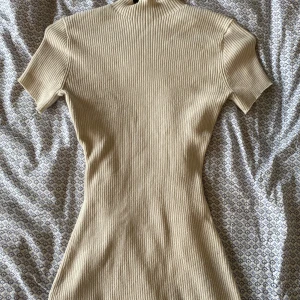 Stickad t-shirt - Säljer en superfin beige ribbad topp från H&M. Den har en tight passform och korta ärmar, perfekt för både vardag och fest. Materialet är mjukt och stretchigt, vilket gör den bekväm att bära hela dagen. Passar perfekt till höst och vår!