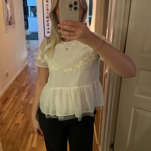 Vit blommig blus från Zara - Säljer en superfin vit blus med korta ärmar och spetsdetaljer från Zara. Den har ett sött blommönster och prickar över hela tyget. 🩷