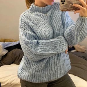 Ljusblå stickad tröja - Säljer en chunky knit ljusblå tröja som är perfekt för kyliga dagar. Den har en avslappnad passform och långa ärmar, vilket gör den både bekväm och stilren. Perfekt för höst och vinter!