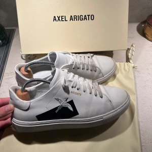 Axel Arigato Skor - Vita arigato skor som är sjukt snygga. Är i använt skick men fortfarande i väldigt fint skick. Box och dust bag får man me. Vid snabb affär är jag villig att sänka priset lite. Fler frågor bara att skriva till mig!