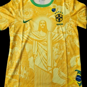 Gul Brasilien fotbollströja - Snygg gul Brasilien fotbollströja från Nike med gröna detaljer. Tröjan har ett unikt mönster med Kristusstatyn och andra brasilianska symboler. Perfekt för fotbollsfans som vill sticka ut!