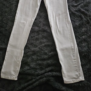 Vita jeansbyxor - Snygga vita jeansbyxor med en klassisk design. De har en rak passform och är perfekta för en stilren look. Byxorna har fickor fram och bak samt knapp- och dragkedjestängning.