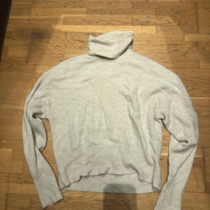 Beige polotröja - Mysig beige polotröja med ribbade detaljer. Perfekt för kyliga dagar med sin höga krage och långa ärmar. En klassisk och stilren design som passar till det mesta.