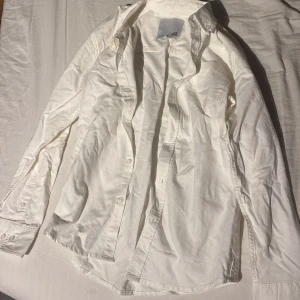 Vit skjorta från 157 - Säljer en klassisk vit skjorta från 157. Skjortan har långa ärmar och knappar framtill. Perfekt för en stilren look.