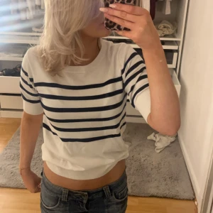 Vit och marinblå randig tröja - Säljer en stilren vit tröja med marinblå ränder. Tröjan har korta ärmar och en rund halsringning. 