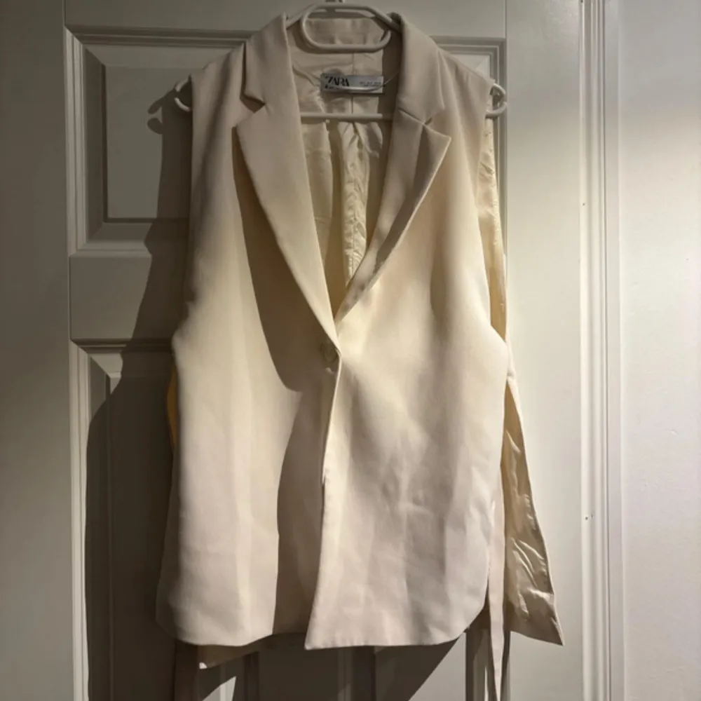 Elegant beige väst från Zara med knytband i sidan. Perfekt för en stilren look.. Muu.