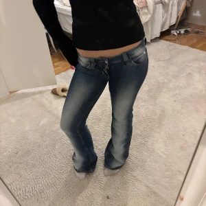 Blå bootcut jeans - Snygga blå bootcut jeans med låg midja och klassisk femficksdesign. Perfekta för en avslappnad stil med en lätt tvättad look. Passar utmärkt till både sneakers och klackar.