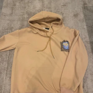 Beige stussy hoodie - Säljer en beige hoodie från Stussy med tryck på bröstet och ryggen. Hoodien har en justerbar huva och ribbade muddar. Perfekt för en avslappnad stil. 