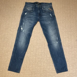 Replay anbass med slitningar  - Snygga blå jeans från Replay med slitna detaljer. Dessa jeans är unika men väldigt fina och stiliga. De är i storlek W29. Skick: 9/10 eftersom att de är uppsydda där nere. Vid frågor och funderingar är det bara att kontakta mig 