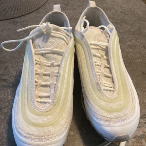 Nike Air Max sneakers i vitt och beige - Snygga Nike Air Max sneakers i vitt och beige med klassisk design och synlig luftdämpning i sulan. Skorna har snörning och en stilren look som passar perfekt för en sportig stil.