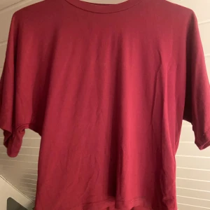Topp vinröd - Snygg vinröd topp från lager 157. I princip nyskick. Den sitter tajt i midjan och pösigare uppåt. 