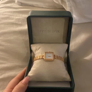 Guldfärgad klocka från Ivy N Rox - Elegant rosé färgad  klocka från Ivy N Rox med fyrkantig urtavla och romerska siffror. Klockan har en länkarmband i guldton och kommer i en stilren förvaringsbox. Storlek saknas då jag fick den som gåva 