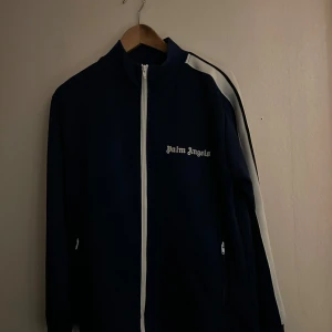 Mörkblå Tracksuit överdel från Palm Angels - Säljer en snygg mörkblå Tracksuit överdel från Palm Angels. Den är min brors och han behöver hjälp med att sälja den! Helt ny då tröjan va för liten men byxorna passade! Nypris cirka 4-5 tusen. Jag lägger ut den för 1699 men kan gå ber vid snabb afärr!🤩Då han köpte Tracksuiten på rea! Har online kvitto om de önskas!🤩
