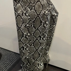 Ormskinnsmönstrade stövlar från Tiamo - Snygga stövlar med ormskinnsmönster från Tiamo. De har en spetsig tå och hög klack, vilket ger en elegant look. Perfekta för att göra ett statement. Använd 1 gång. Låda är kvar.