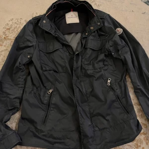 Marinblå jacka från Moncler - Snygg Marinblå jacka från Moncler med dragkedja. Köptes från Vestiaire och gick då också genom en äktighets check, har däremot inget kvitto eller liknande. Det är en äldre modell som är sjukt snygg men säljer tyvärr för den blivit för liten(14y är storleken men passar s/xs när jag va 170cm funkar bra för längre/kortare. Använd men är i bra skick (inga skador eller så) luvan går även att ta bort om man inte vill ha den. Vid Frågor eller fler bilder skriv! Pris kan diskuteras!!