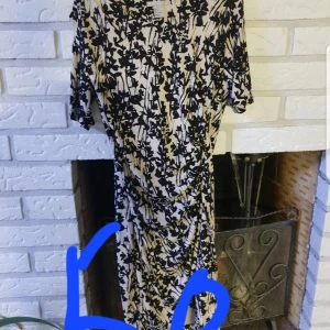 Blommig klänning med korta ärmar - Snygg klänning med blommigt mönster i svart och beige. Den har korta ärmar och en smickrande passform. 38/40