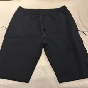 Svarta shorts från Moncler - Snygga svarta shorts från Moncler med snörning i midjan och praktiska fickor. Perfekta för en avslappnad stil. Tillverkade i bomull för extra komfort.