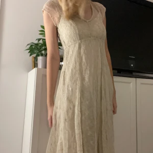 Beige spetsklänning från Vintage Stories - Säljer en superfin beige spetsklänning från Vintage Stories. Den har en romantisk vintage stil med korta ärmar och en v-ringad hals, slutar mitten på låren.Perfekt för fester och vardag! Klänningen är i storlek 36 och kommer med beige underklänning 💕