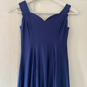 Blå långklänning med breda axelband - Säljer en elegant blå långklänning med breda axelband och en slit. Klänningen har en vacker passform och är perfekt för festliga tillfällen. Materialet är mjukt och faller fint, vilket ger en lyxig känsla.