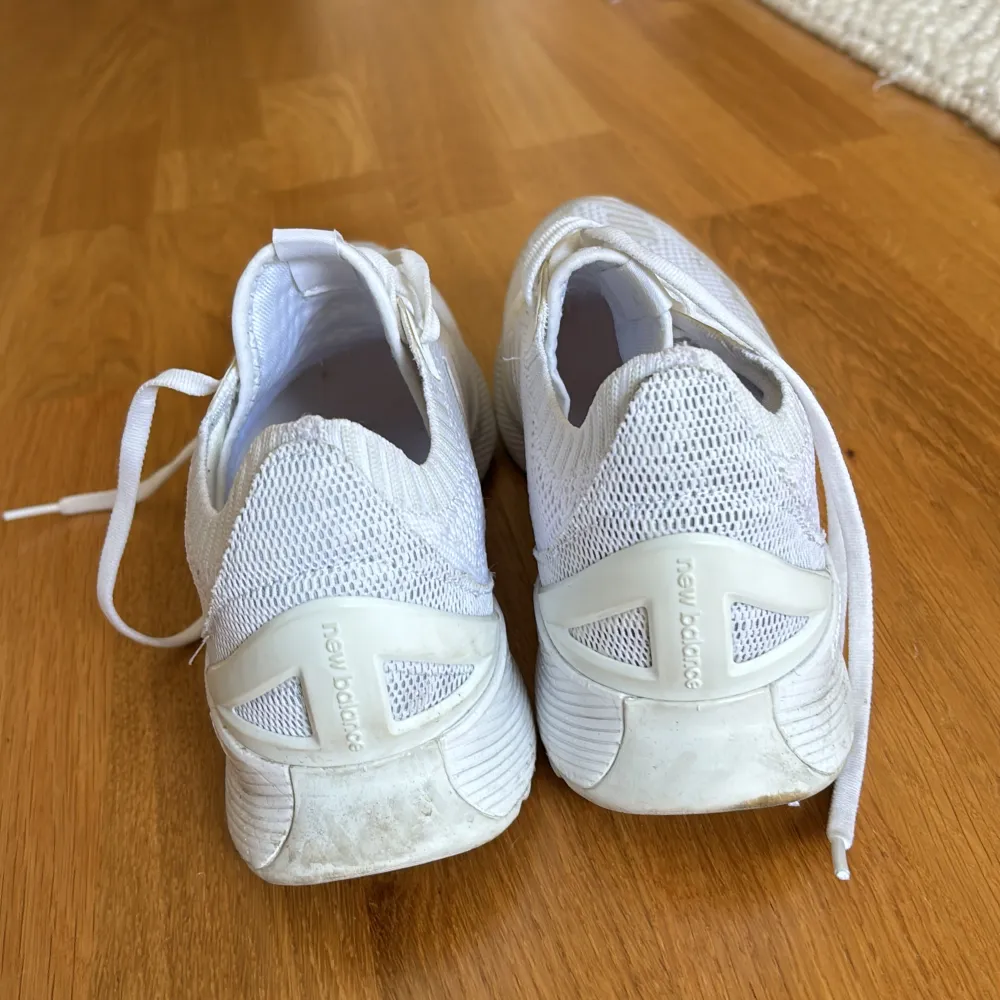 Säljer ett par vita sneakers från New Balance i storlek 40,5. Skorna är i bra skick och har en snygg och stilren design med snörning. Perfekta för både träning och vardagsbruk. De är gjorda i ett lätt och andningsbart material som gör dem bekväma.. Skor.