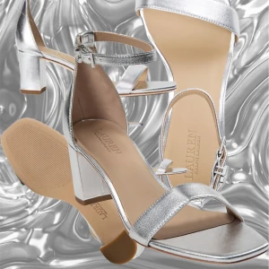 Lauren Ralph Lauren sandaler -  silvriga sandaler med klack från Lauren Ralph Lauren. De har en elegant design med en smal rem över tårna och en justerbar rem runt ankeln med dragkedja. Perfekta för festliga tillfällen eller en utekväll. Klacken ger en stilren look och de är bekväma att bära hela kvällen. 