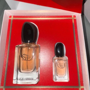 Giorgio Armani Sì parfymset - Säljer ett lyxigt parfymset från Giorgio Armani med två flaskor av doften Sì. Den större flaskan har en elegant svart kork och den mindre är perfekt för resor. Förpackningen är stilren med en röd och guldig design. Perfekt present eller för att unna sig själv! 🌟 Köpt för 900kr