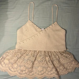 Supersnygg topp från Zara💕 - Säljer en söt beige topp från Zara med spetsdetaljer och smala axelband. Toppen har en omlott-design och knytband i ryggen🥰