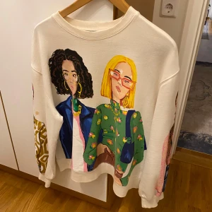 Vit tröja med tryck från Zara - Säljer en cool vit tröja från Zara med färgglatt tryck av olika karaktärer på framsidan och ärmarna. Tröjan har en rund hals och långa ärmar, perfekt för en unik och stilren look.