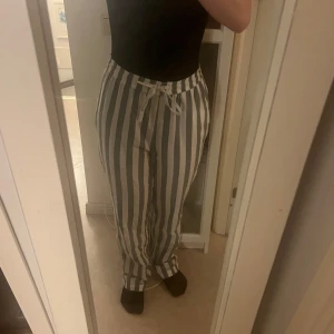 Randiga byxor med snörning - Snygga randiga byxor i vitt och grått med bekväm passform. De har en praktisk snörning i midjan för justerbar passform. Perfekta för en avslappnad stil.