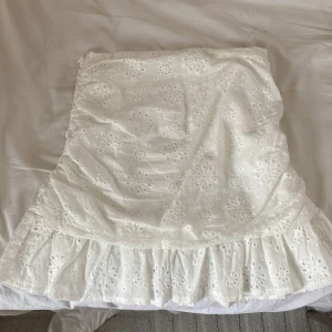 Vit kjol från Shein - Säljer en söt vit kjol från Shein med broderade blommönster och volangdetaljer. Perfekt för en somrig look. Har aldrig använt eftersom det inte fanns något tillfälle. 