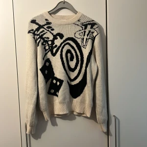 Beige stickad tröja från Nike - Säljer enl beige stickad tröja från Nike X Stussy i storlek M med svart grafiskt mönster. Tröjan har långa ärmar och en avslappnad passform. Perfekt för att ge din outfit en unik touch! Säljer den då jag råkat tvätta den i torktumlaren och den blev lite för kort för mig så rekommenderar att inte göra det. Passar M och S. Ny pris var 3300kr