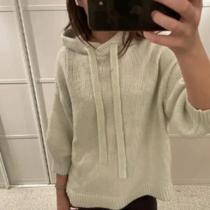 Beige stickad hoodie - Mysig beige stickad hoodie med långa ärmar och dragsko i huvan. Perfekt för kyliga dagar och ger en avslappnad look. Passar bra till jeans eller leggings.