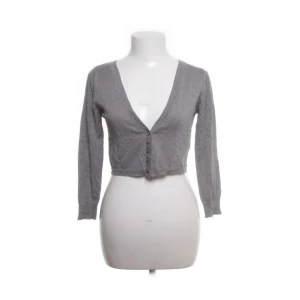 Grå croppad kofta - Säljer en stilren grå croppad kofta med knappar framtill. Perfekt för lager-på-lager och har en djup v-ringning. Bra skick 