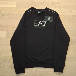 Svart tröja från Emporio Armani - Helt ny Tröja från Emporio Armani, EA7. Den är aldrig använd och är i storlek 160, men passar upp till 170 så ungefär XS. Meddela gärna om du är intresserad eller vill diskutera pris ✅️